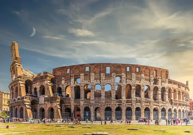 El Coliseo en Roma es un imponente anfiteatro de piedra, con arcos superpuestos y una estructura monumental que evoca la grandeza del Imperio romano.