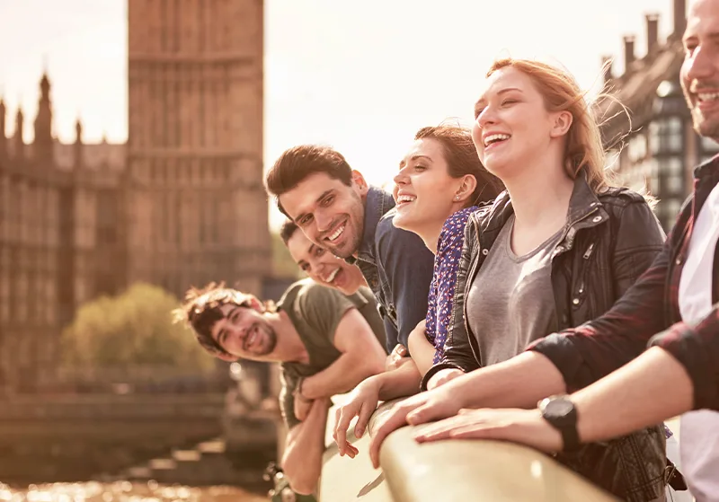 Grupo de amigos observando un río desde un puente histórico durante un viaje por Europa.