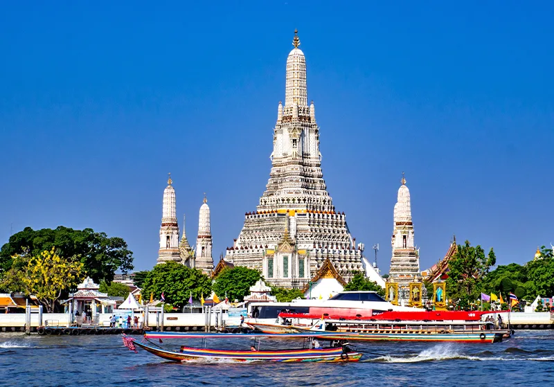 Templo Wat Arun (Templo del Amanecer) a orillas del río Chao Phraya con barcos tradicionales de cola larga en Bangkok, Tailandia