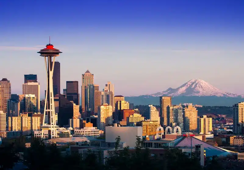 Panorama urbano de la ciudad de Seattle con la emblemática torre Space Needle y el Monte Rainier al fondo.