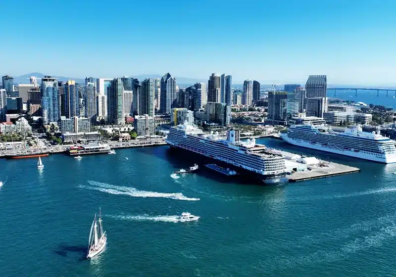 Vista panorámica del Puerto de San Diego con barcos navegando y los rascacielos del centro de la ciudad al fondo bajo un cielo despejado.
